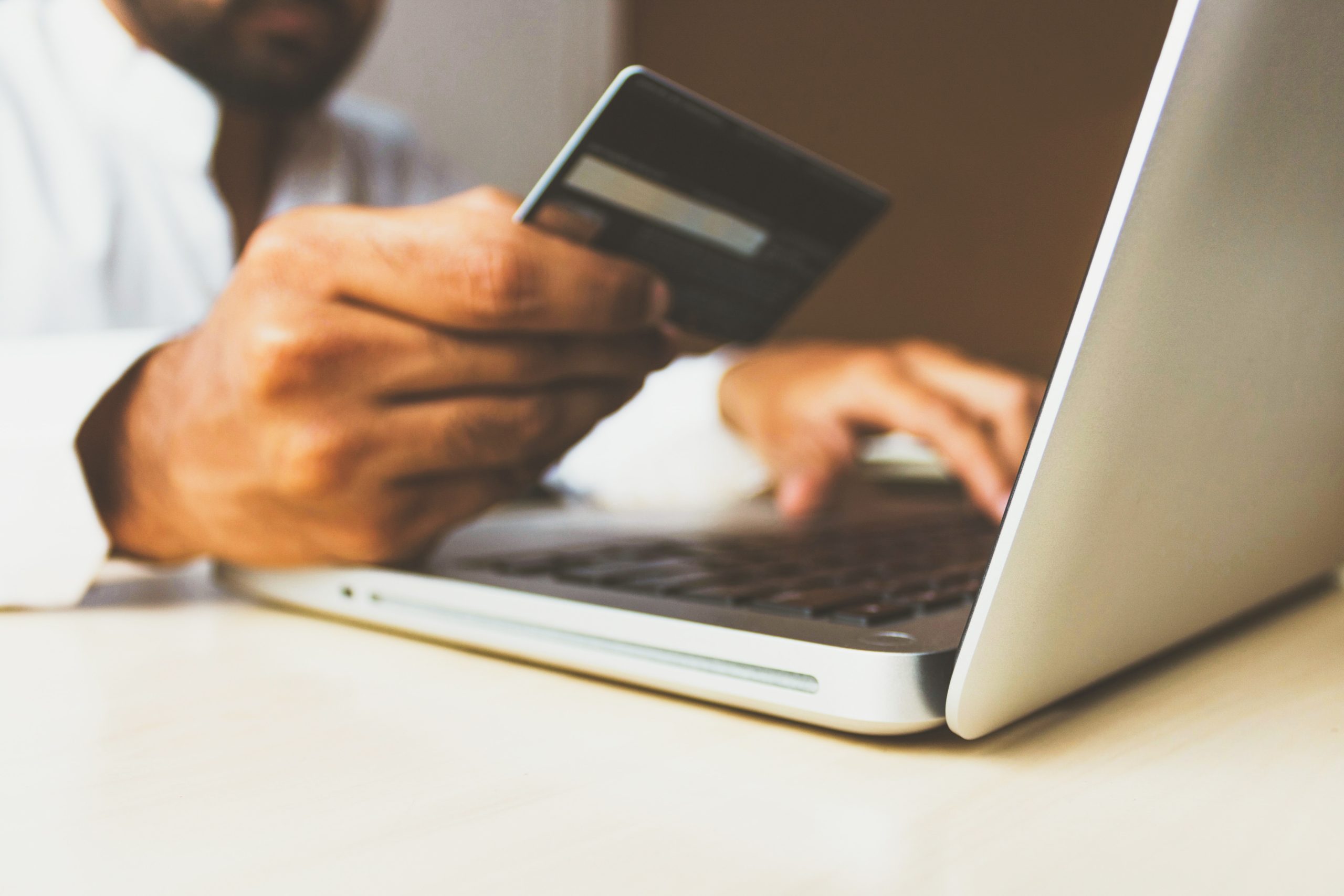 Man in front of a laptop holding up a credit card