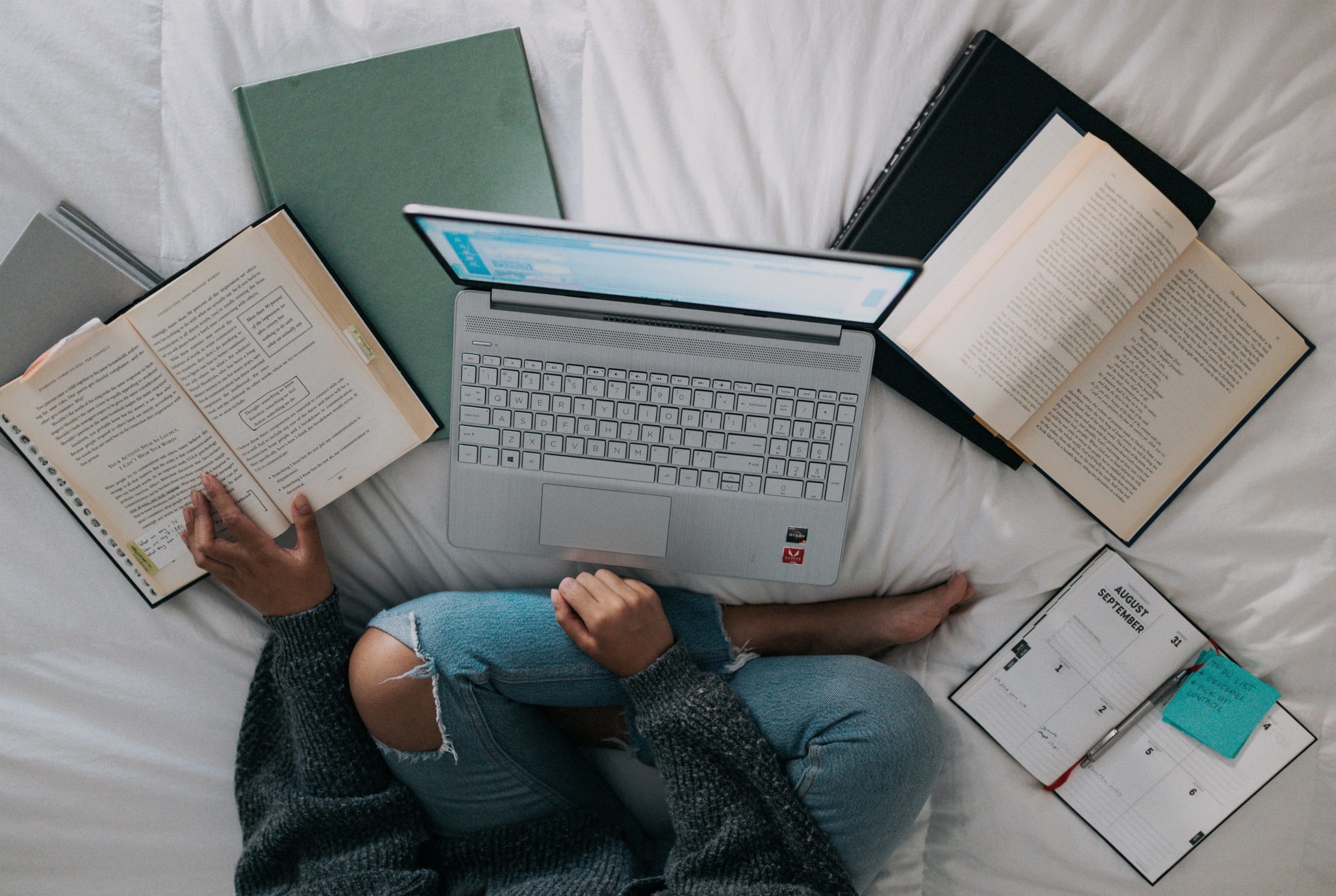 Online further training setup in bed with books and a laptop